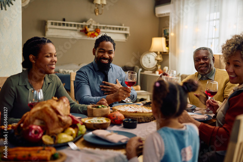 Happy black extended family talks during Thanksgiving meal at dining table.
