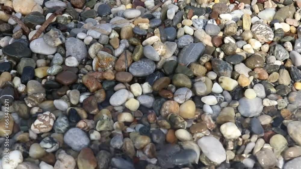 Piedras en la playa siendo mojadas por el agua del mar. Piedras de diversas formas y colores Piedras en la playa siendo mojadas por el agua del mar. Piedras de diversas formas y colores