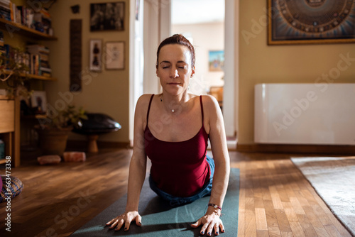 Young woman doing yoga in the living room at home photo
