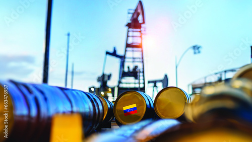Focus on a barrel with a sticker in the colors of the Venezuela flag. On the blurry background some oil extractors