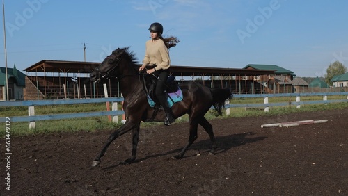 Riding a horse in an equestrian club. Rider training before the competition. Young woman riding a horse, rides in an equestrian club. Woman equestrian riding a horse on a training field.