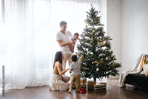 Fotografie Happy Asian family decorating Christmas tree together in the living room at home