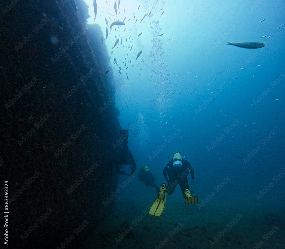 three divers diving in a sunken ship