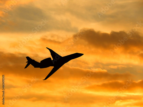 Silhouette of a private executive jet taking off against a winter sky at sunset. No people. Copy space.