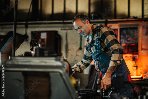 A metallurgy machinist operating a metal turning machine in a workshop.