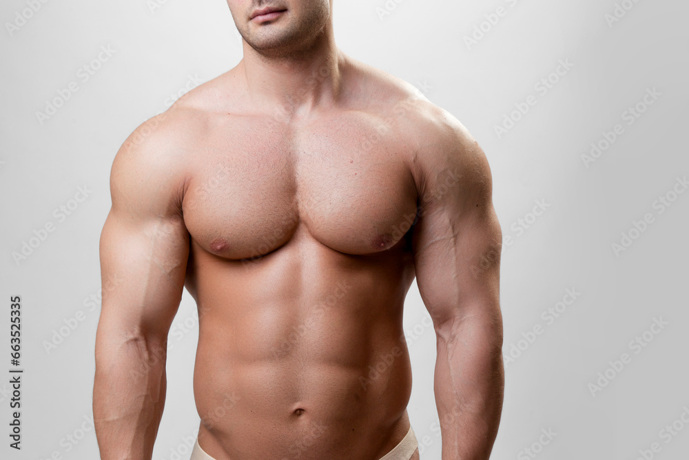 MFront image of a muscular athlete fit bodybuilder man on a gray background