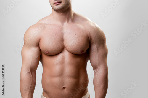 MFront image of a muscular athlete fit bodybuilder man on a gray background