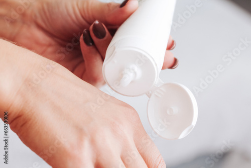 Skin care background. Hand cream use. Closeup of skin and container. Cosmetics background. Hands moisturizing. Body lotion in white tube. Caucasian female lifestyle applying cream background.