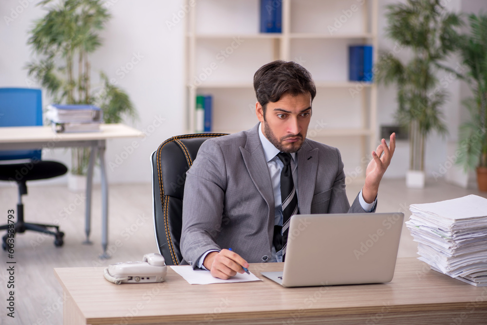 Young male employee and too much work in the office Young male employee and too much work in the office
