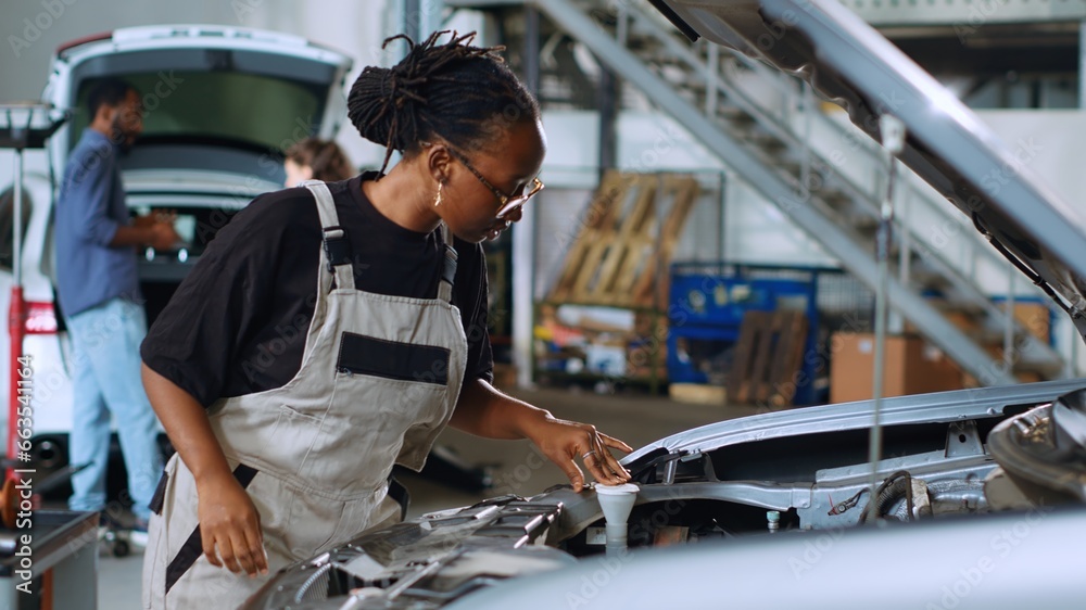 Knowledgeable mechanic in garage using torque wrench to tighten screws inside opened up vehicle, preparing to change oil. Auto repair shop employee doing checkup on car to prevent defects