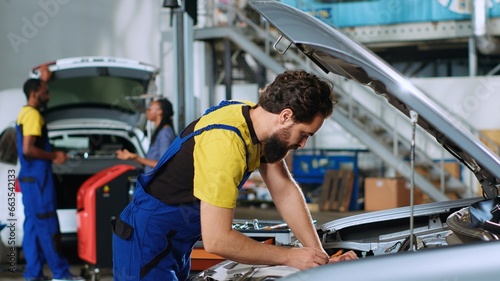 Mechanic in car service uses torque wrench to tighten bolts inside vehicle after fixing components inside. Repair shop employee utilizing professional tools to make sure automobile is properly working