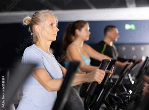 Mature woman exercising on an elliptical trainer in the gym