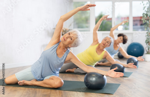 Group of elderly women practicing pilates with soft ball in fitness studio