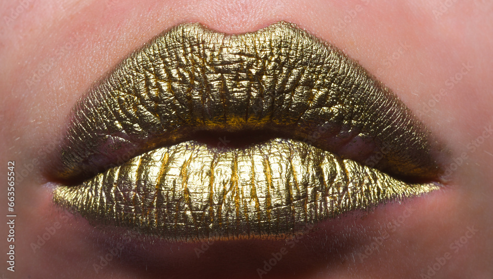 Fototapeta premium Gold lips, golden lipgloss on sexy lips, metallic mouth. Beauty woman mouth. Sexy girl golden lips, gold mouth. Glowing gold skin and gild lips. Metallic shine golden lip gloss.