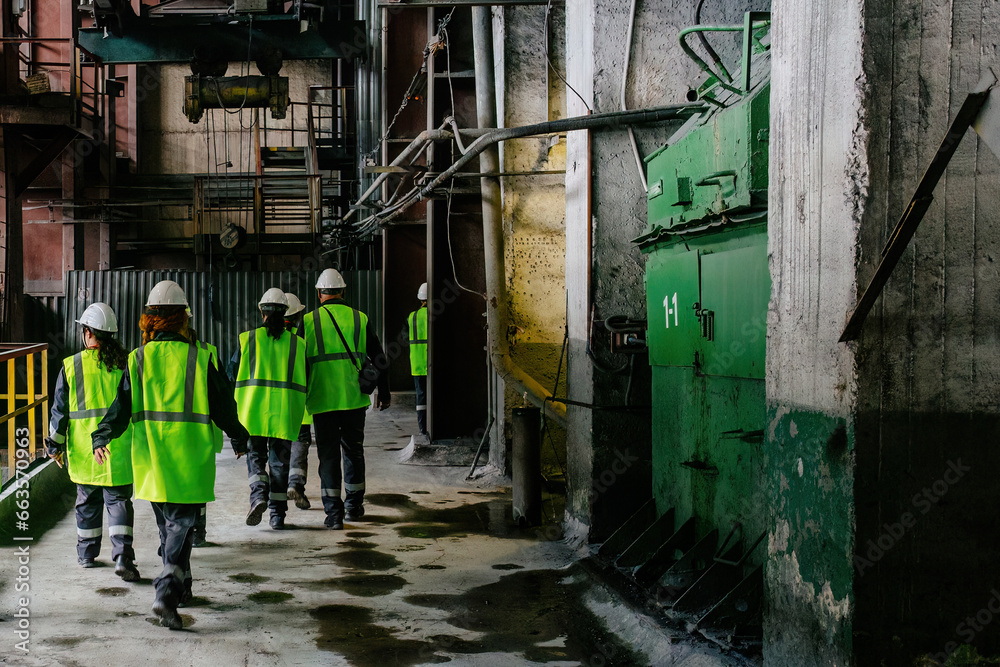 Group of workers in uniform walking along the corridor of factory