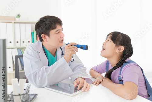 asian doctor use flashlight and diagnosis children patient in hospital, children open her mount and show her tongue, child clinical screening, happiness hospital