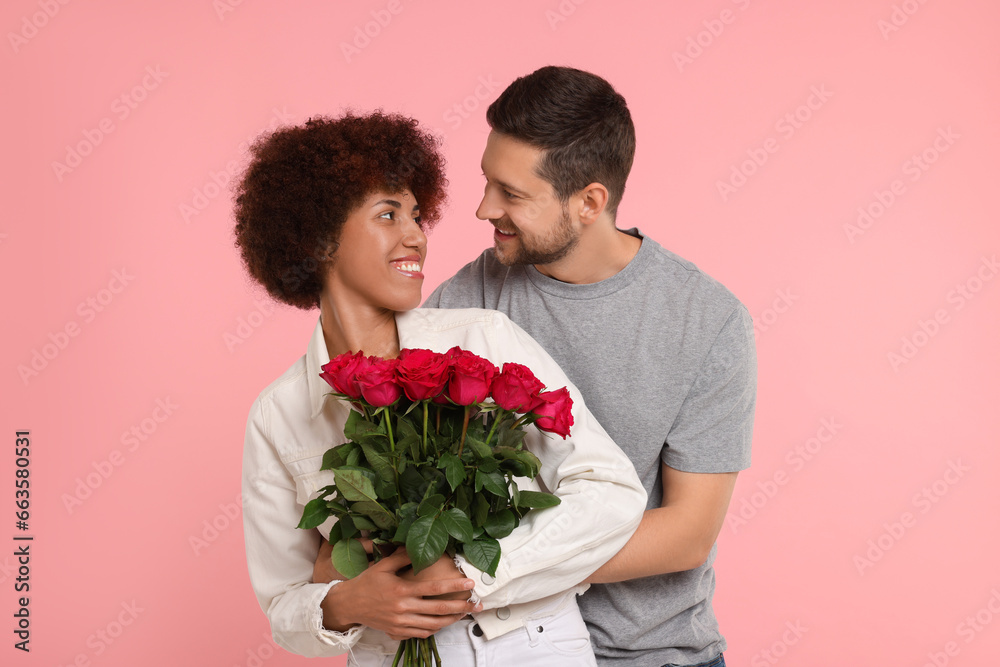 International dating. Lovely couple with bouquet of roses on pink background International dating. Lovely couple with bouquet of roses on pink background