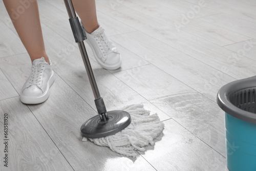 Woman cleaning floor with mop indoors, closeup