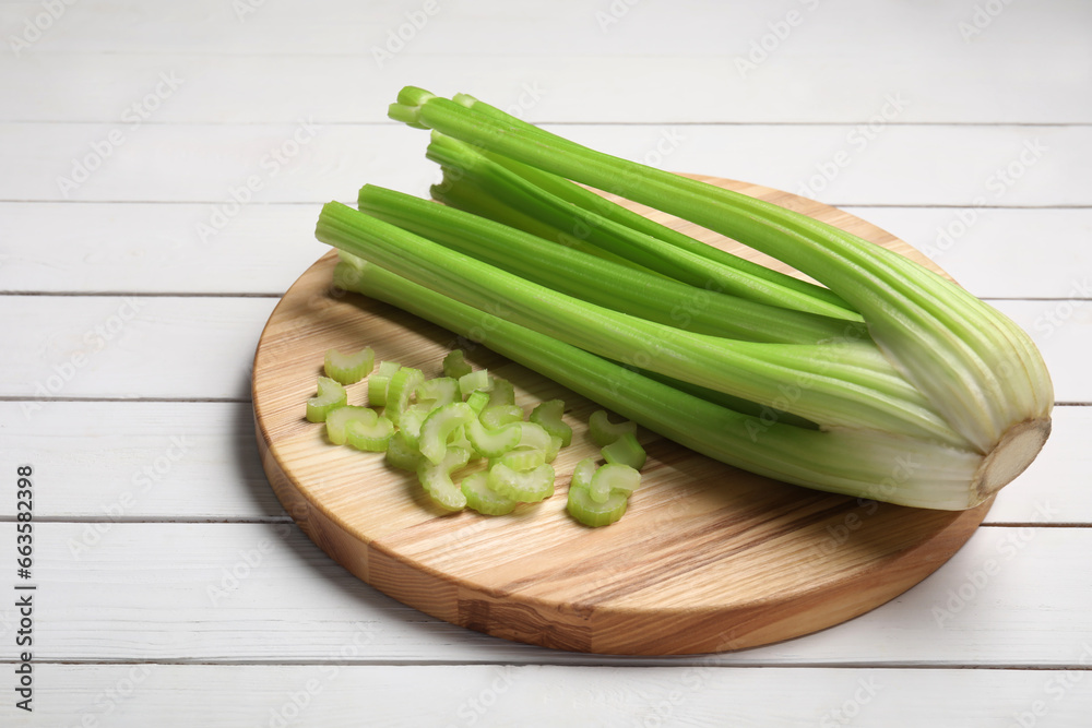 Board with fresh cut and whole celery on white wooden table, space for text Board with fresh cut and whole celery on white wooden table, space for text