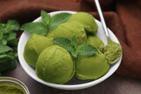 Tasty matcha ice cream and spoon with powder in bowl on table, closeup