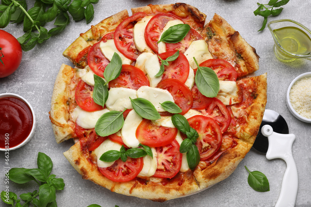 Delicious Caprese pizza with tomatoes, mozzarella and basil on light grey table, flat lay
