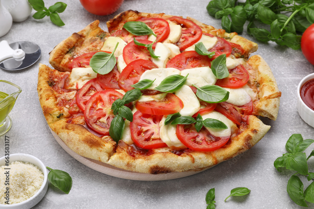 Delicious Caprese pizza with tomatoes, mozzarella and basil on light grey table