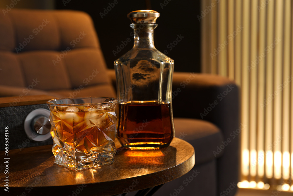 Bottle and glass of whiskey on wooden table in room, space for text. Relax at home Bottle and glass of whiskey on wooden table in room, space for text. Relax at home