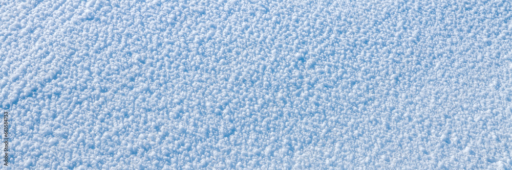 Obraz premium Natural snow texture. The surface of an icy snow crust. Snowy ground. Winter background with snow patterns. Perfect for Christmas and New Year design. Closeup top view.