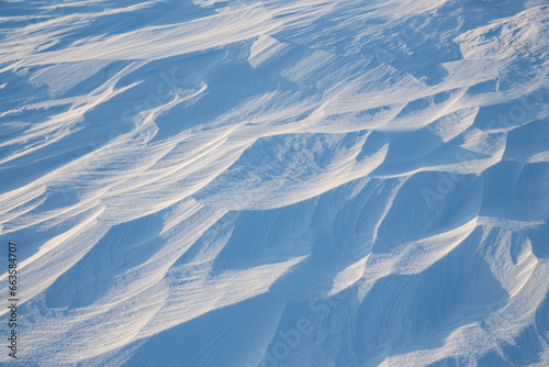 Snow texture. Wind sculpted patterns on snow surface. Wind in the tundra and in the mountains on the surface of the snow sculpts patterns and ridges (sastrugi). Arctic, Polar region. Winter background © Andrei Stepanov