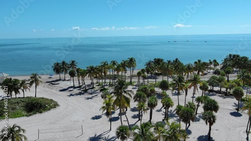 aerial footage of a gorgeous summer landscape at Crandon Park with vast blue Atlantic ocean, lush green palm trees and people on the sandy beach in Key Biscayne Florida USA photo