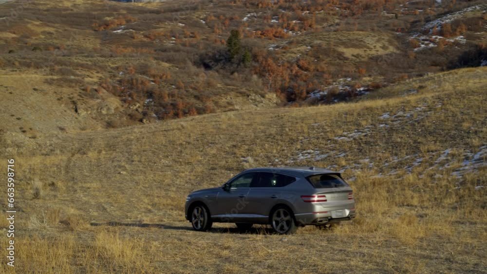 Wide, drone shot around van driving up autumn hill Wide, drone shot around van driving up autumn hill
