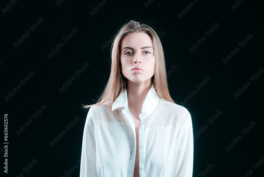 Elegant young woman in shirt posing over black background. Light and shadow. Portrait of a beauty woman face. Elegant young woman in shirt posing over black background. Light and shadow. Portrait of a beauty woman face.