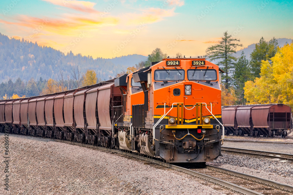 freight train in autumn with a beautiful sunset sky close to Whitefish, Montana - obrazy, fototapety, plakaty 