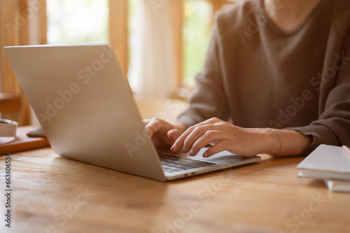 A woman using her laptop at a table in a beautiful, cosy coffee shop. typing on keyboard