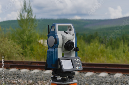 tachometer making geodetic survey with green summer forest at the background