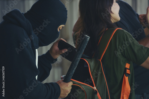rob aggressive by danger bandit. Thief using baton nightstick weapon. Thief armed man rob woman by baton on street stalker behind young woman back. Woman on phone careless stalker sneaking to steal