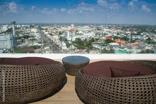 Woven wicker seamless pattern table and chairs is basketwork by weaving plastic strands to oval or sphere shape . Brown wicker sofa on the rooftop for see view of the city with sunlight background. © sornchai