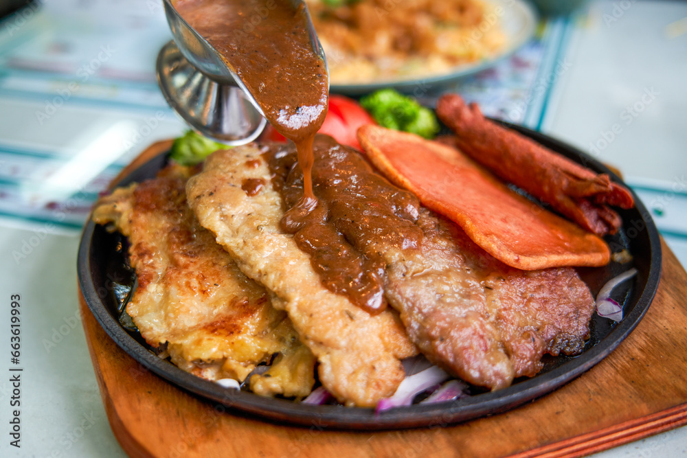 A delicious and tempting sizzling steak, chicken, and pork chop in a Hong Kong-style tea restaurant A delicious and tempting sizzling steak, chicken, and pork chop in a Hong Kong-style tea restaurant