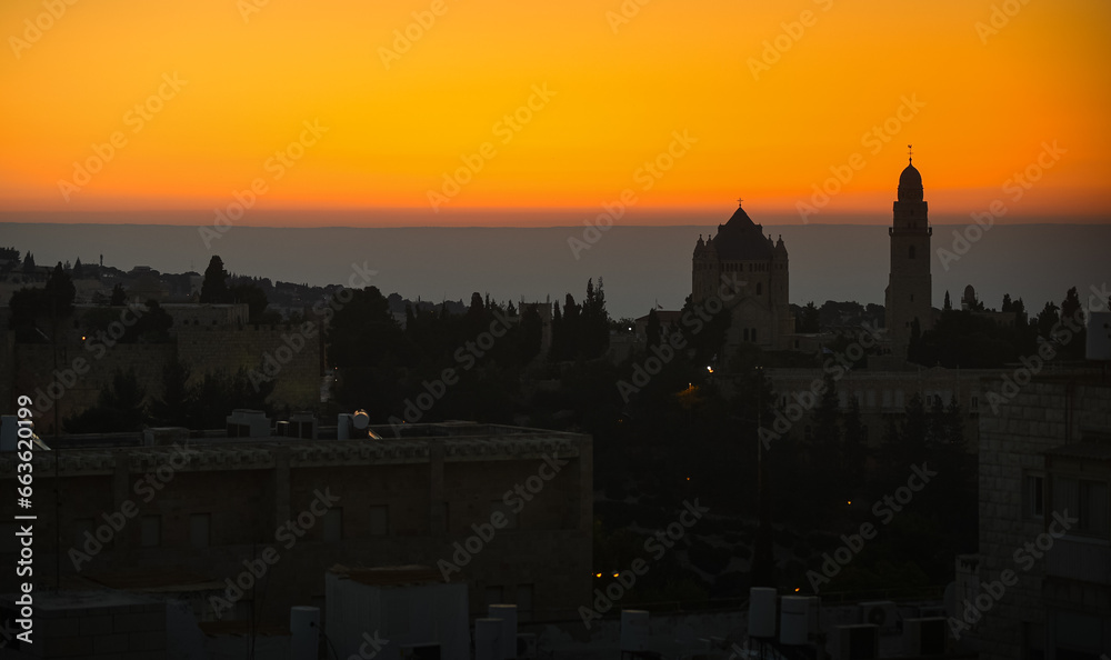 Fototapeta premium Dramatic sunrise in Israel. Synagogue view from above against orange sky and mountains line background. Sunrise view in Jerusalem, concept image for this war times.