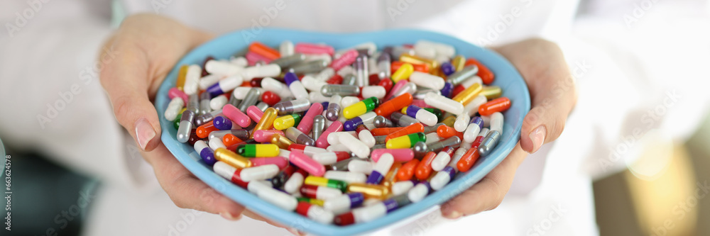 Doctor holds heart-shaped plate with colorful pills in hands