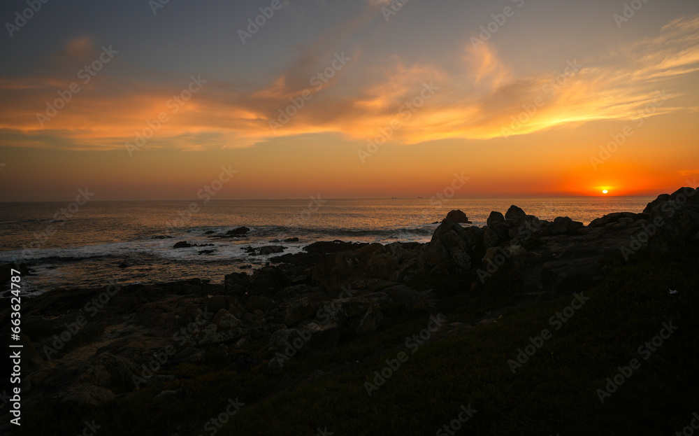 Sunset over the ocean. Beautiful orange sky landscape at the Atlantic Ocean, view from Porto, Portugal. Amazing sea view with rocks and waves.