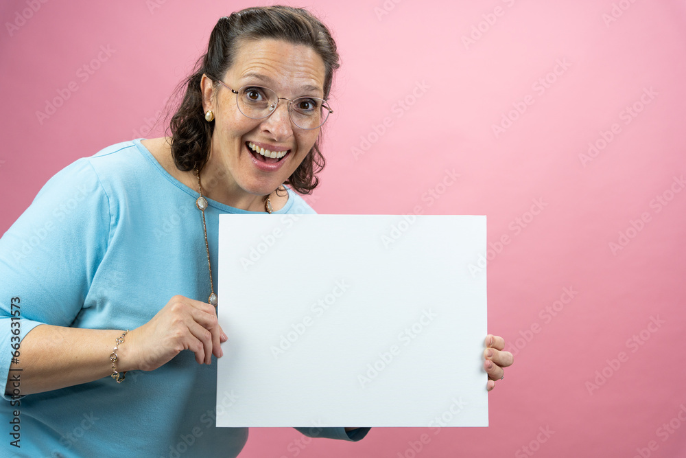 Mature Businesswoman in Blue Blouse on Colored Background holding a sign with room for copy Mature Businesswoman in Blue Blouse on Colored Background holding a sign with room for copy
