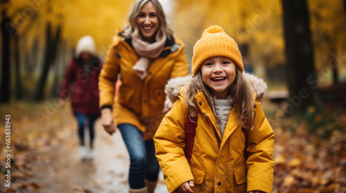 A young girl and her mother go for a walk through a forest in autumn