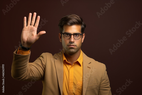 Professional-looking man in suit and glasses is making stop sign gesture. This image can be used to depict caution, warning, or traffic safety concepts. © vefimov