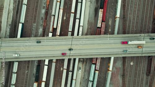 top down aerial of a bridge overpass above multiple rail roads with trains freight. Red Semi truck driver is driving a reefer - dryvan. Great concept for delivering freight logistics companies. photo