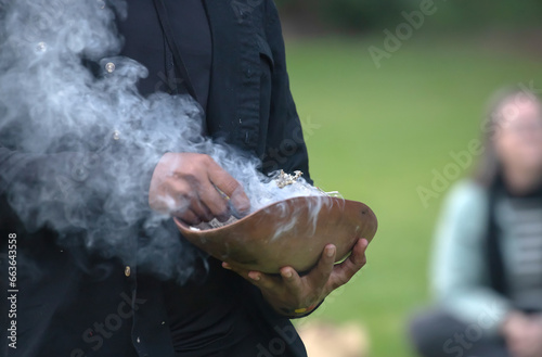 Bild auf Leinwand Human hands hold wooden ceremonial dish with smoked branches, the welcome ritual