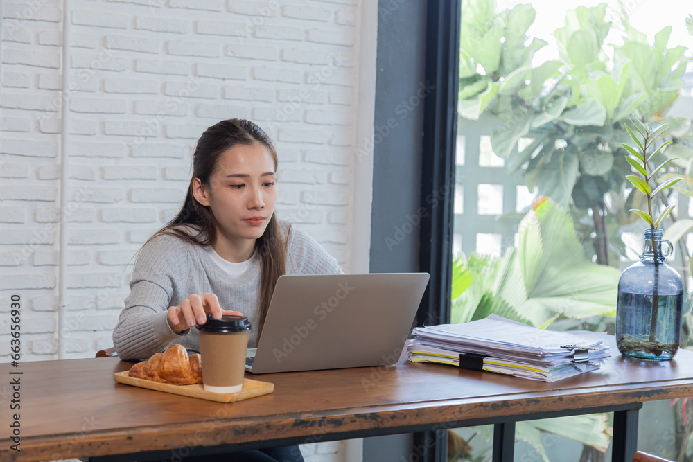 Beautiful working Asian woman sitting in coffee shop checking work with laptop. Attractive businesswomen everywhere or freelancer concentrate on stacks of documents, waiting for friends at cafe. Beautiful working Asian woman sitting in coffee shop checking work with laptop. Attractive businesswomen everywhere or freelancer concentrate on stacks of documents, waiting for friends at cafe.