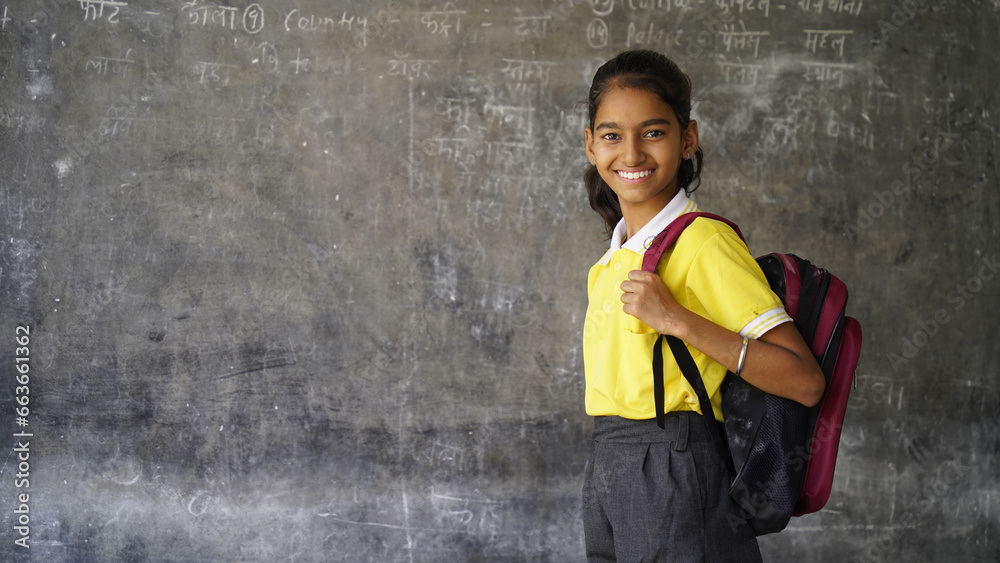 Portrait of happy indian teenager school girl with backpack holding books. Smiling young asian female kid looking at camera. - obrazy, fototapety, plakaty 