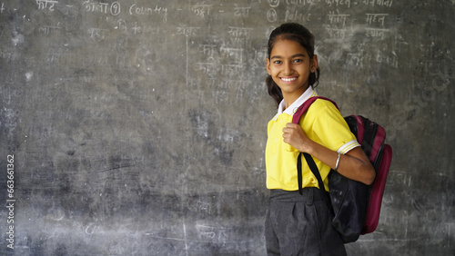 Portrait of happy indian teenager school girl with backpack holding books. Smiling young asian female kid looking at camera. photo