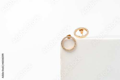 Golden earrings on display on white background